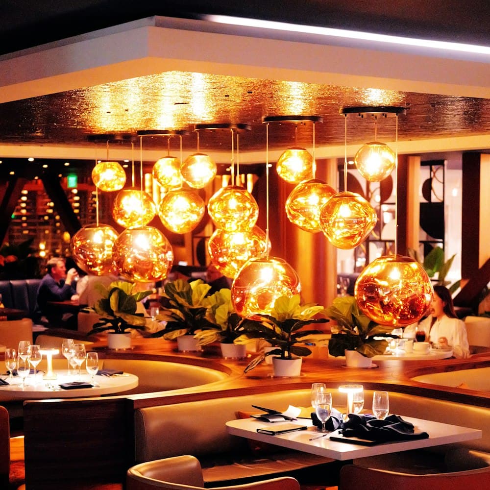 Luxurious modern restaurant interior with warm ambient lighting and set tables.