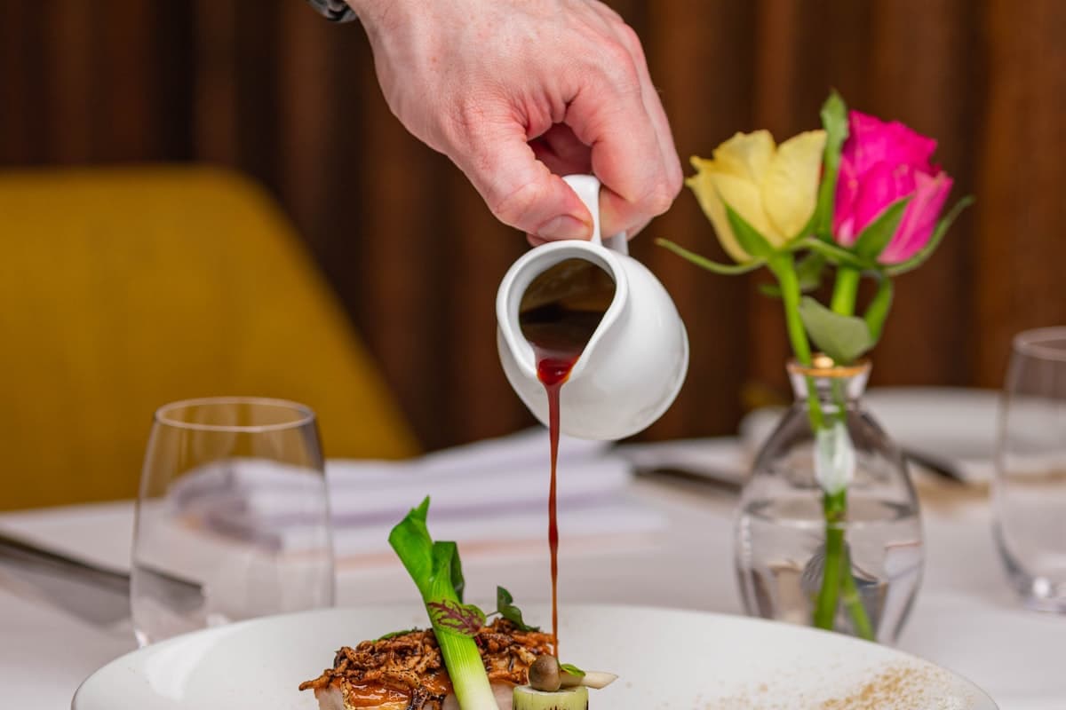 Chef finishing a plate with tweezers in a professional kitchen, shallow depth of field.