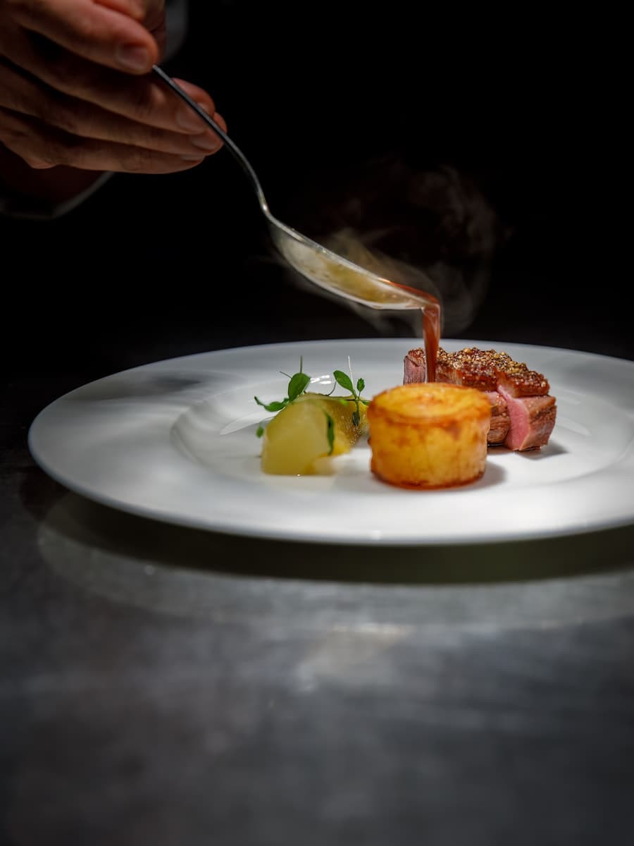 Sliced A5 wagyu striploin, medium-rare, on a dark slate board with charred leeks.